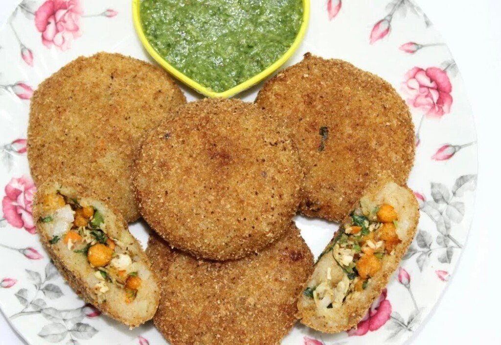 Crunchy chunky aloo tikkis, two cut open to show the stuffing, with green chutney