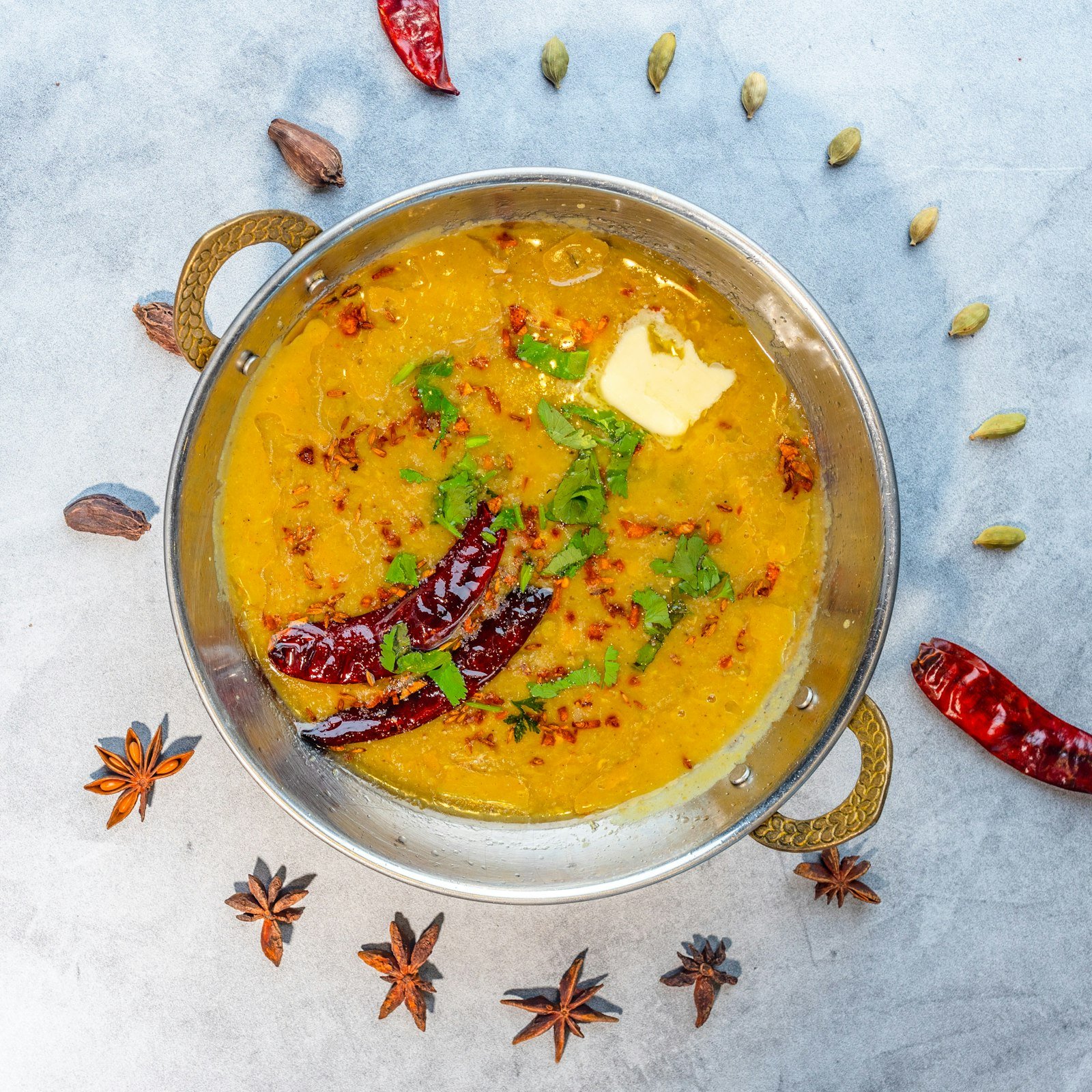 Dal served in a small kadai with dried red chillies and spices around it