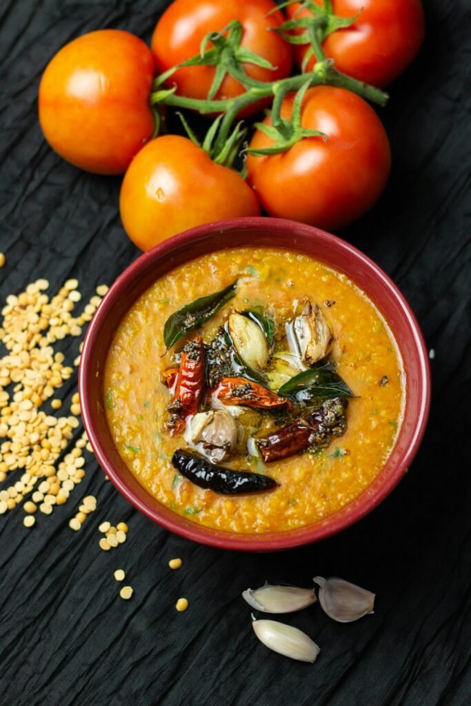A bowl of yellow dal topped with a tadka of dried red chillies and curry leaves