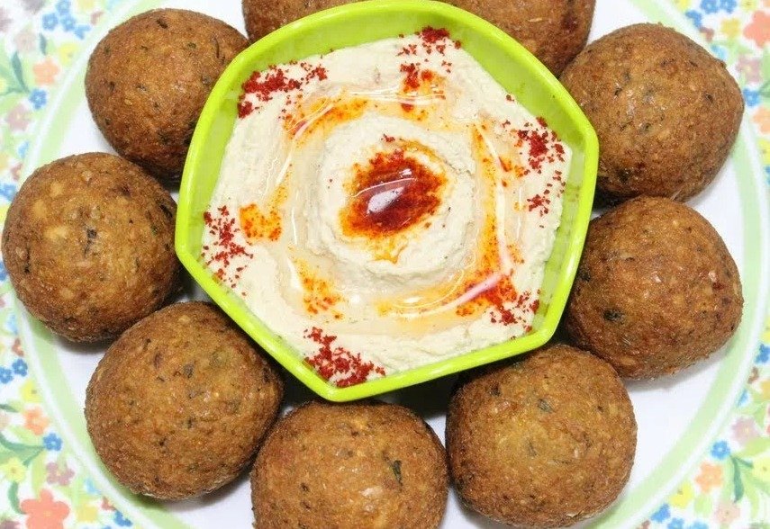 Golden falafel arranged around a bowl of hummus