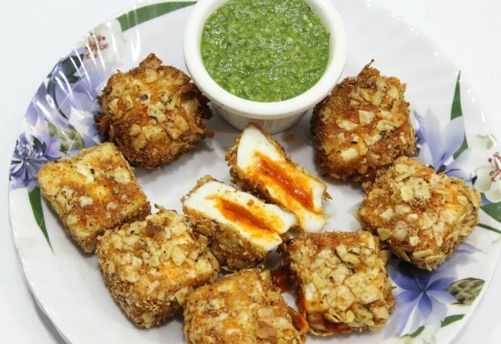 Crispy schezwan-stuffed khasta paneer cubes with green chutney on a plate