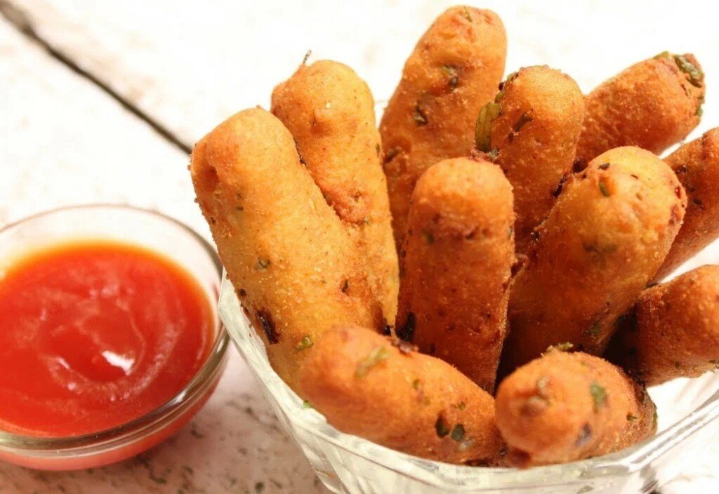 Golden paneer fingers in a glass bowl with tomato ketchup